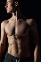 athlete with a naked torso looks to the side on a black background photo