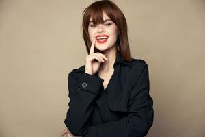 Funny woman black coat charming smile laughing on a beige background photo