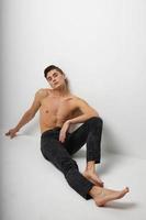 handsome man sitting on floor black pants naked torso posing photo