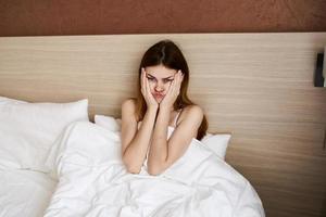 woman woke up early in the morning and touch her face with her hands under the covers in bed photo