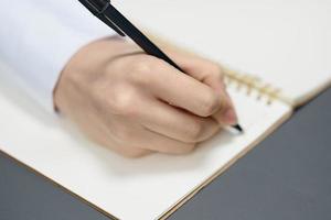 Closeup shot of hand young student lady freelancer journalist writing article using copybook in gray modern home office. Remote Job, Education And Career Profession Concept. Copy space photo