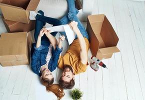 A man and a woman with boxes are moving. Well, an apartment is being renovated by a family photo