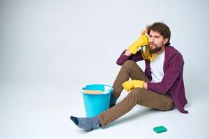 Cleaner sits on the floor with a bucket of homework service room interior photo