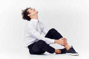 man with curly hair in a classic suit and sneakers sits on the floor and side view Copy Space photo