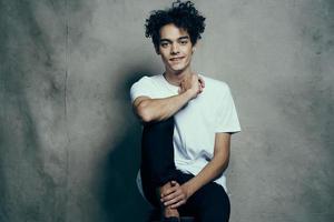 cute guy with curly hair in a white t-shirt sits on chairs studio fashion photo