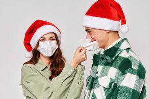 young couple in christmas hats medical masks close-up gray background photo