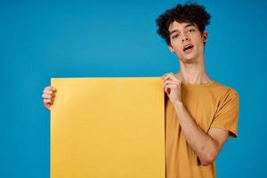 guy with curly hair of yellow asters in his hands studio blue background photo