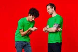 Two man green t-shirts embrace emotions friendship red background photo