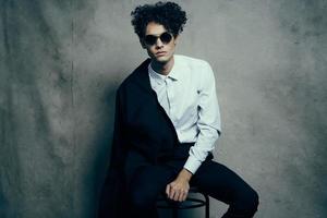 trendy guy with curly hair indoors on a fabric background and a jacket on the shoulder photo