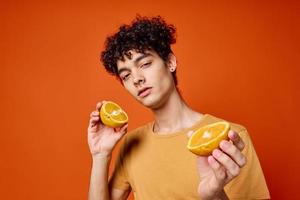 handsome man with curly hair oranges in hands studio isolated background photo