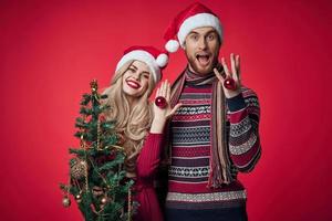 man and woman are standing next to New Years holiday Christmas gifts photo