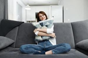 woman hugging pillow on sofa comfortable rest at home photo