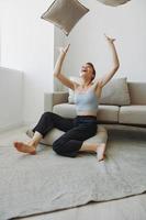 Teenage girl smile everyone sits at home near the couch and tosses up pillows, fun game and happiness without filters, copy place photo