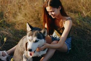 Woman sitting in field with dachshund dog smiling while spending time outdoors with dog friend photo