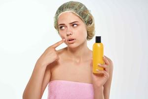 woman in pink towel yellow jar with body care cream photo