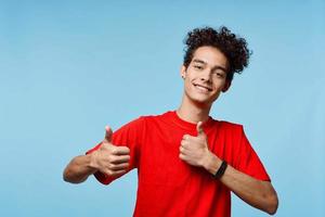 Cheerful guy with curly hair in a red t-shirt gestures with his hands photo