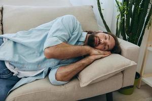 un hombre dormido en el sofá durante el día es cansado y relajado después estrés y sensación malo. estrés a trabajar, pobre dormir y salud problemas foto