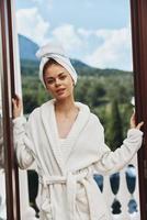 beautiful woman in a white robe on the balcony bit on green nature Perfect sunny morning photo