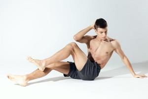 atlético chico en pantalones cortos haciendo ejercicios en un brillante habitación carrocero foto