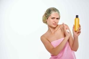 woman with unhappy facial expression in pink towel lotion skin care photo