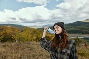 Smiling woman with medical mask on nature in the mountains in the forest photo