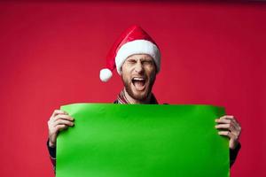 alegre hombre en un Papa Noel sombrero participación un bandera fiesta rojo antecedentes foto