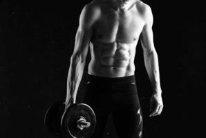 man with dumbbells in his hands naked muscular body workout dark background photo