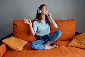 sonriente mujer auricular a hogar en el sofá entretenimiento inalterado foto