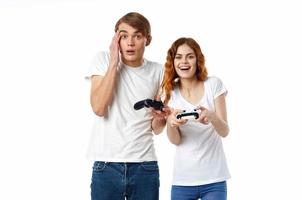joven Pareja en blanco camisetas con palancas de mando en su manos vídeo juegos entretenimiento foto