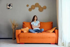 bonito mujer relajante a hogar en el habitación en el sofá interior inalterado foto