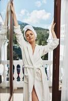 Attractive young woman in a white robe on the balcony bit on green nature Relaxation concept photo