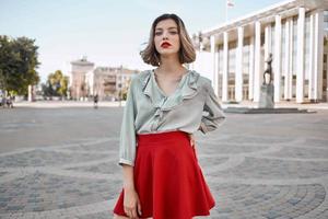 alegre mujer en rojo falda en el cuadrado al aire libre posando foto