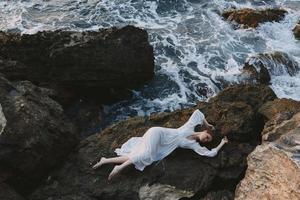 Beautiful bride in a secluded spot on a wild rocky coast in a white dress landscape photo