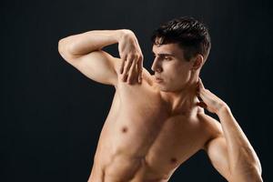 man with a pumped-up torso muscular staircase posing dark background photo