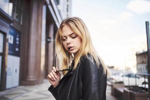 Fashionable woman wearing leather jacket outdoors near the building blonde fresh air photo