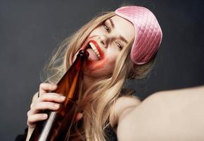 Drunk blonde girl with a bottle of beer gestures with her hands and a bright makeup addiction model photo