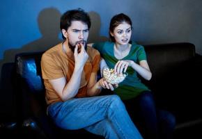 A man and a woman are watching TV in the evening indoors photo