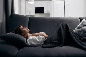 woman covered with a blanket is resting lying on the sofa photo