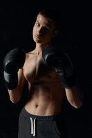 sports guy on a black background in boxing gloves inflated torso cropped view Model Copy Space photo