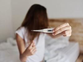 woman showing thermometer close-up looking away photo