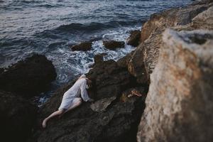 Beautiful bride in a secluded spot on a wild rocky coast in a white dress nature photo