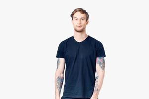 sporty man in a blue t-shirt with tattoos on his arms on a white background Copy Space photo