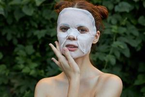 Nice woman Anti-wrinkle mask touch your face with your hand in nature cosmetology bushes photo