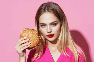 bonito mujer en rosado camisa con hamburguesa rápido comida dieta foto