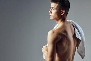 chico con un toalla terminado su espalda desnudo torso rutina de ejercicio atlético mira foto