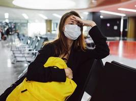 woman wearing medical mask eyes closed airport yellow backpack photo