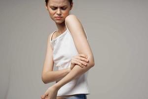 disgruntled woman rheumatism elbow pain health problems light background photo