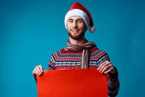 emocional hombre en un Papa Noel sombrero participación un bandera fiesta azul antecedentes foto