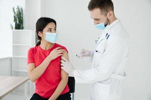 male doctor in a medical mask injecting a female patient in the shoulder covid vaccination photo