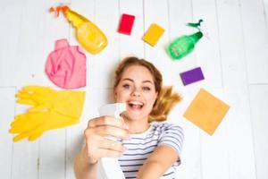 mujer en a rayas camiseta mentiras en el piso limpieza suministros detergente tareas del hogar foto